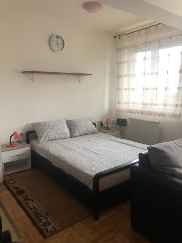 a bedroom with a bed and a clock on the wall at Tulipan in Sombor