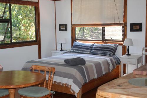 a bedroom with a bed and a table and window at Treehouse Cottage in The Crags