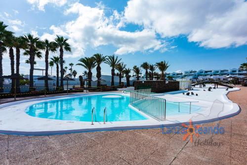 a swimming pool with palm trees in a resort at Vivienda Vacacional Las Coronas 48 in Costa Teguise