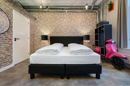 ein Schlafzimmer mit einem Bett und einem rosa Roller in der Unterkunft The Monument Hotel in Den Haag