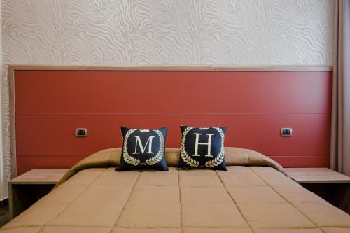 a bed with two pillows with the letter m on it at Miryam House Affittacamere Suite e Relax in San Severo