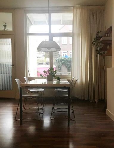 a dining room table with chairs and a large window at Appartement Rotterdam Noord in Rotterdam