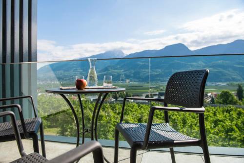 a table and chairs on a balcony with a view at Hotel Törggelehof in Cermes