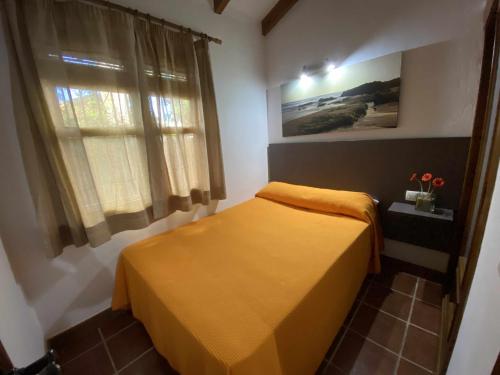 - une chambre avec un lit doté d'un couvre-lit jaune et d'une fenêtre dans l'établissement Casa Bungalows con jardín privado y piscina compa, à Cadix