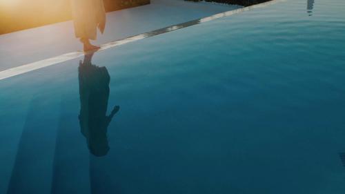 a person standing on the edge of a swimming pool at The Island Concept Luxury Boutique Hotel Heated Pool in Agios Nikolaos