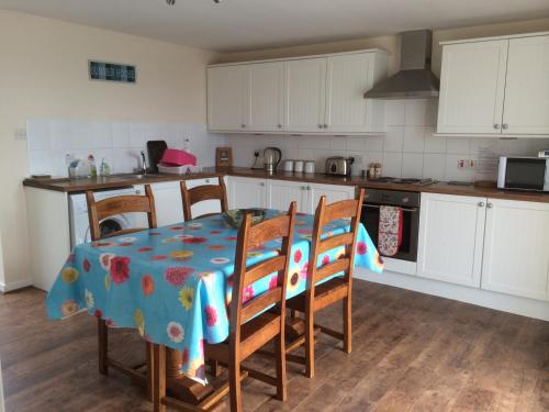 a kitchen with a table and chairs and a kitchen with white cabinets at Lovely 3-Bed Cottage Portmahomack next to harbour in Portmahomack