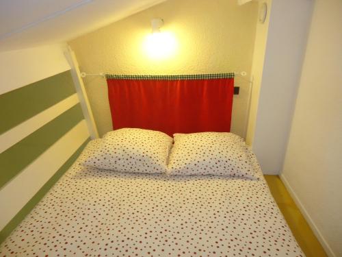 a small bedroom with a bed with a red curtain at Résidence Thibaud in Toulouse