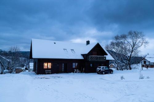 a snow covered house with a truck parked in front of it at Cisna Chata - Bieszczady in Cisna