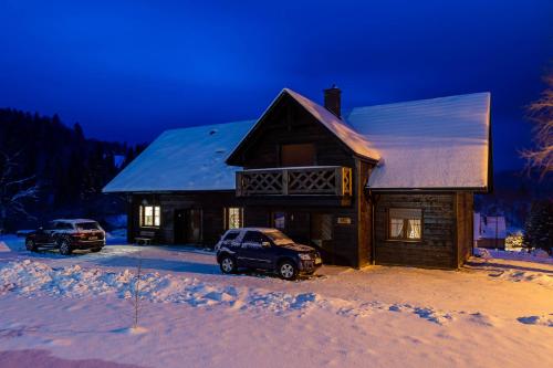 a log cabin with two cars parked in the snow at Cisna Chata - Bieszczady in Cisna