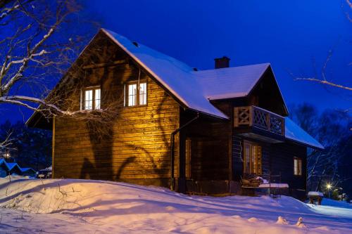 a wooden house in the snow at night at Cisna Chata - Bieszczady in Cisna