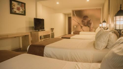a hotel room with three beds and a television at Termales Santa Rosa De Cabal in Santa Rosa de Cabal