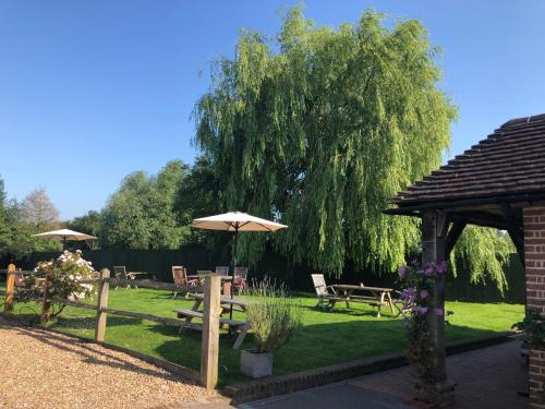 a garden with tables and umbrellas and a tree at The Crown Inn Dial Post in Horsham