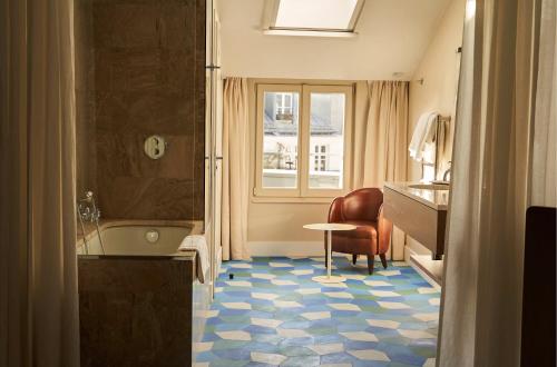 a bathroom with a tub and a sink and a chair at H&ocirc;tel du Sentier in Paris
