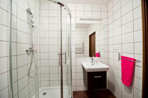 a white tiled bathroom with a shower and a sink at Apartamenty Parkowe in Bydgoszcz