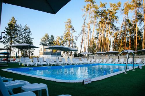 Клуб відпочинку Dacha في Sokirno: مسبح بكراسي بيضاء ومظلات