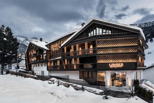 a large wooden building in the snow at Linder Cycling Hotel in Selva di Val Gardena