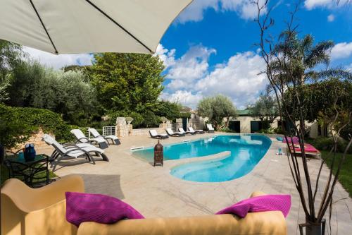 a swimming pool with chairs and an umbrella at Stone House Modica in Modica