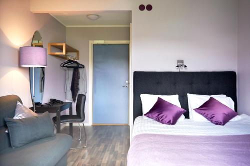 a bedroom with a bed with purple pillows and a desk at Hotel Surte in Surte