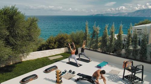 a woman doing yoga on the roof of a house at The Island Concept Luxury Boutique Hotel Heated Pool in Agios Nikolaos
