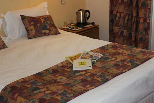 a hotel room with a bed with a book on it at Logis Le Relais de Fusies in Lacaune