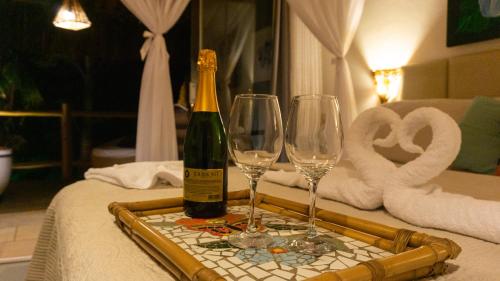 a bottle of champagne and two wine glasses on a table at Xamã Senses - Hotel Pousada in Pipa