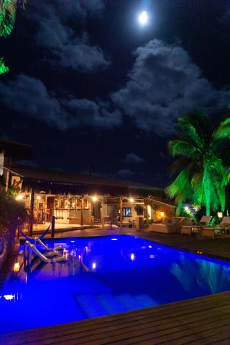 a swimming pool at night with a full moon at Xamã Senses - Hotel Pousada in Pipa