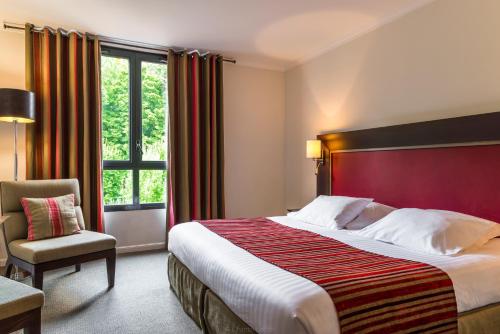 Pokój hotelowy z dużym łóżkiem i krzesłem w obiekcie Hôtel du Golf w mieście Lumbres