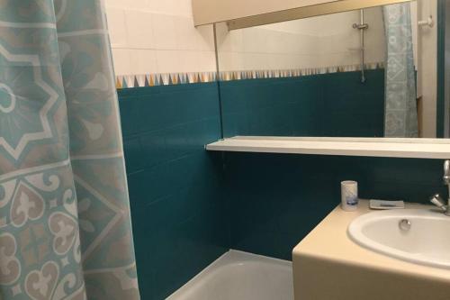 La salle de bains est pourvue d'un lavabo et d'un mur bleu. dans l'établissement studio avec climatisation WIFI parking piscine, au Cap d'Agde