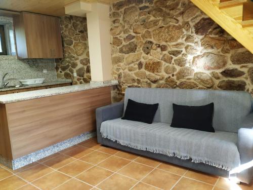 a living room with a couch and a stone wall at Casa del Autón - Couto Mixto in Rubiás