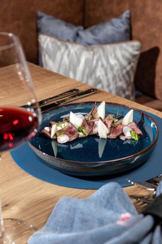 a plate of food on a table with a glass of wine at Linder Cycling Hotel in Selva di Val Gardena