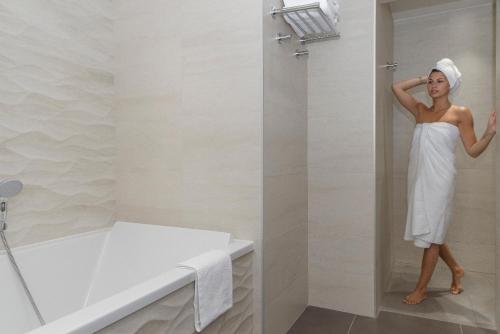 a woman standing in a bathroom with a towel on her head at Hôtel du Parc in Hardelot-Plage
