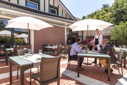 a group of people sitting at tables with umbrellas at Hôtel du Parc in Hardelot-Plage