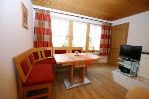 a living room with a table and a couch and a television at Haus Scheglmann inkl. Chiemgaukarte in Ruhpolding