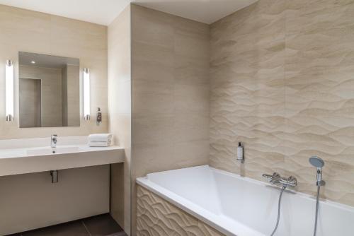 a bathroom with a bath tub and a sink at Hôtel du Parc in Hardelot-Plage