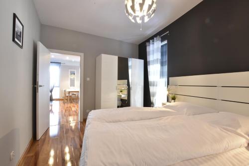 a bedroom with two white beds and a chandelier at Apartament Flauta Pogorzelica in Pogorzelica