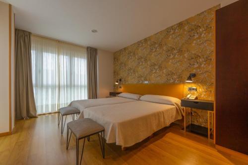 Una habitación de hotel con una cama grande y una pared de piedra. en Hotel Playa de Laxe, en Laxe