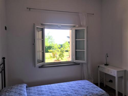 una camera da letto con finestra, letto e scrivania di Tenuta Barbadoro agriturismo apartment a Montespertoli