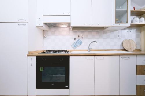 una cocina con armarios blancos y horno negro en Casa Boarni Leuca, en Leuca