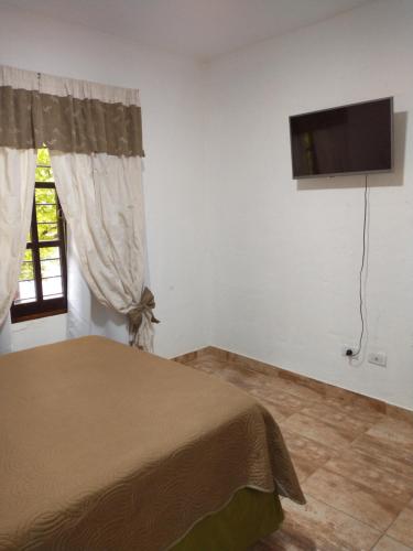 a bedroom with a bed and a flat screen tv at Departamentos Pachamama in Tunuyán