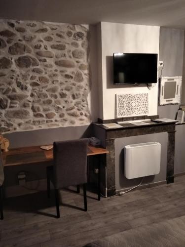 Cette chambre dispose d'un bureau, d'une télévision et d'un mur. dans l'établissement Maison de ville au pied de la Montagne Noire, à Mazamet