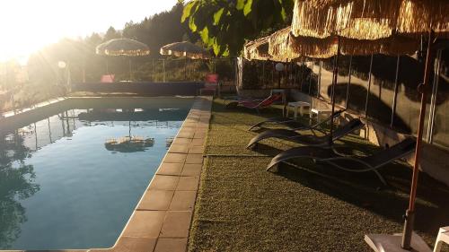 a pool with chairs and a boat in the water at Hôtel - Gîtes "U Pozzu" in Evisa