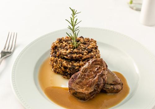 a plate of food with meat and sauce on a table at Estanplaza Funchal Faria Lima in Sao Paulo