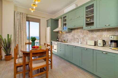 a kitchen with green cabinets and a table and chairs at 2 steps Falasarna beach-Liakos- Homeleader in Falasarna