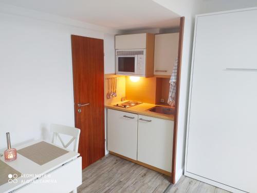 una pequeña cocina con armarios blancos y microondas en HUS WILLEM, en Büsum