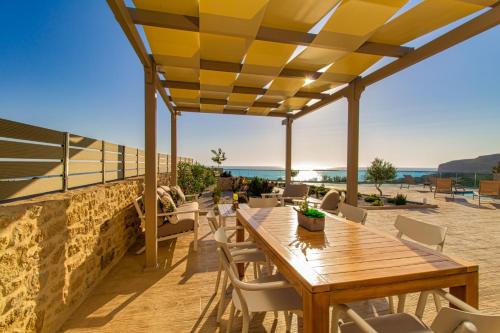 a patio with a wooden table and chairs at 2 steps Falasarna beach-Liakos- Homeleader in Falasarna