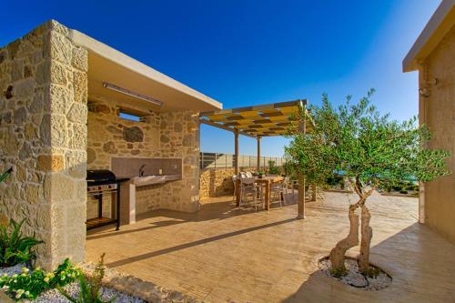 an outdoor patio with a grill and a table with a tree at 2 steps Falasarna beach-Liakos- Homeleader in Falasarna