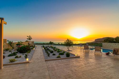 a patio with chairs and a sunset in the background at 2 steps Falasarna beach-Liakos- Homeleader in Falasarna