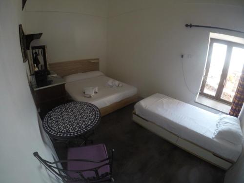 a small room with a bed and a desk and a window at Horizon Pantelleria in Pantelleria