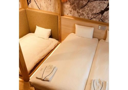 two beds in a small room with a pair of slippers at Sakura Sky Hotel - Vacation STAY 18432v in Tokyo