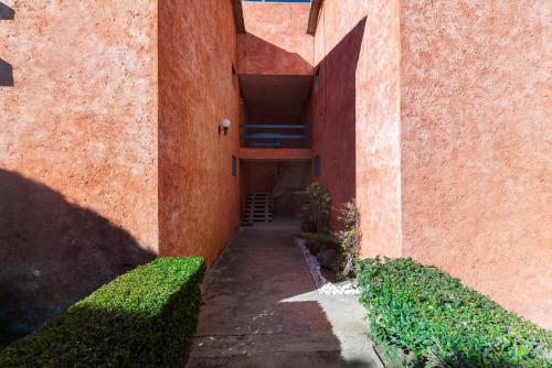 an alley between an orange building with a stairway at +MS +Suite Placentera +Alberca Área verde Quintana 13A in Mendiola